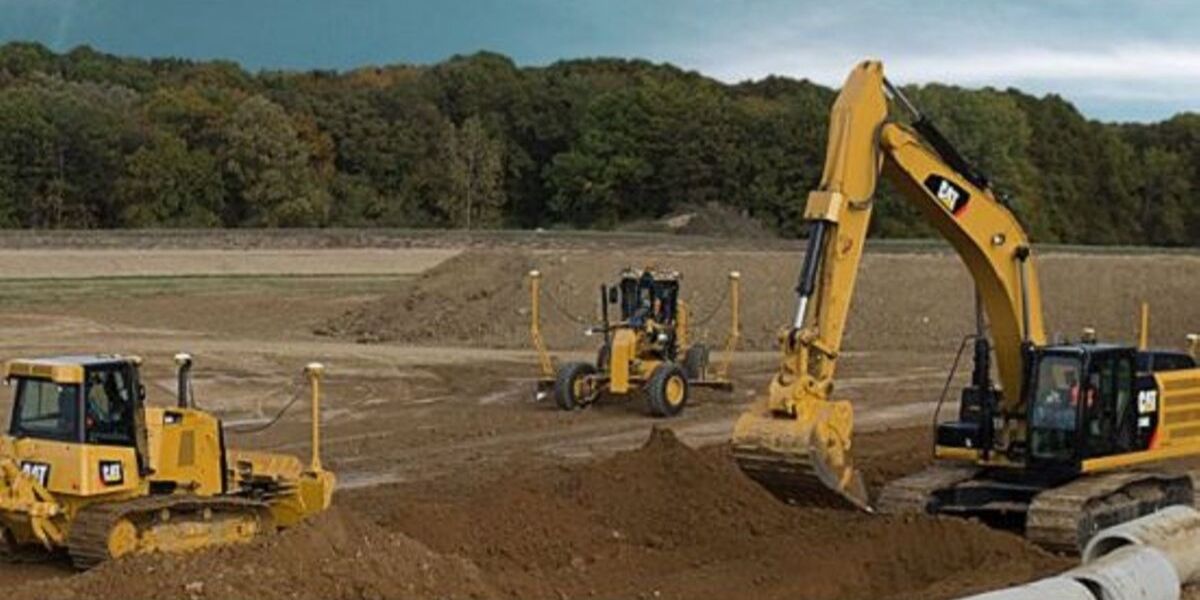 Three construction vehicles working in dirt field