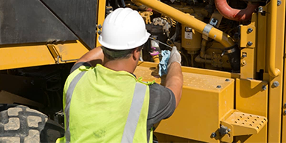 Worker taking oil sample from CAT equipment