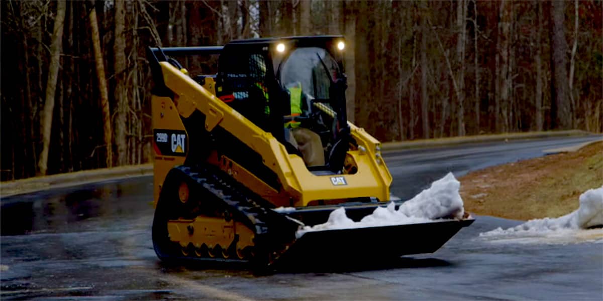Compact track loader lifting snow on road