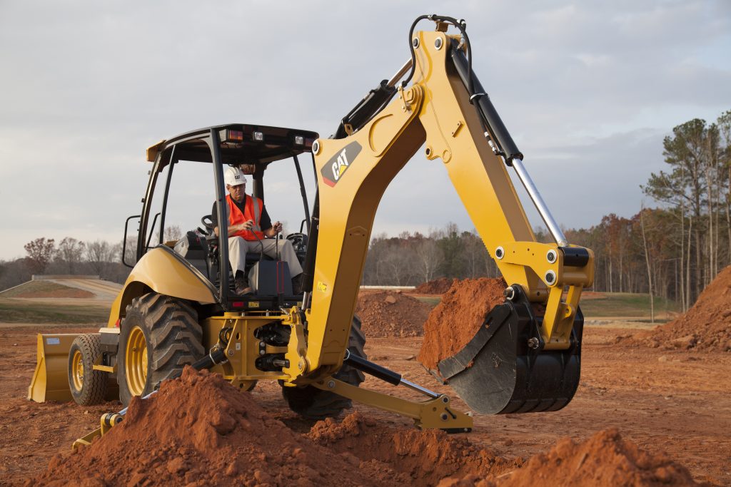 Construction worker driving a yellow CAT Backhoe Loader 