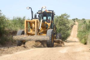 man driving Cat equipment and plowing land